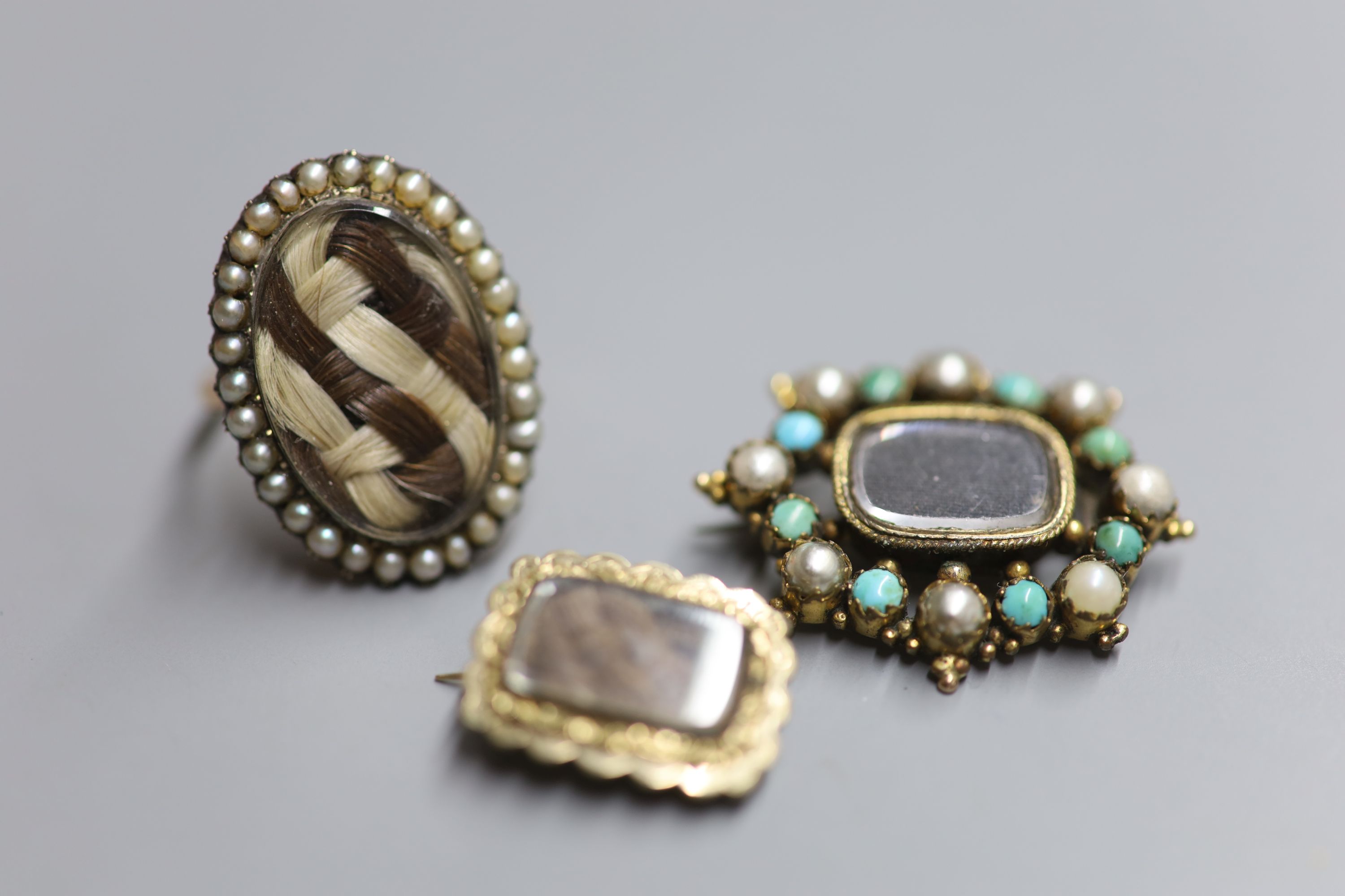 A 19th century yellow metal and seed pearl set oval mourning ring, with plaited hair below a glazed panel & 2 other items.